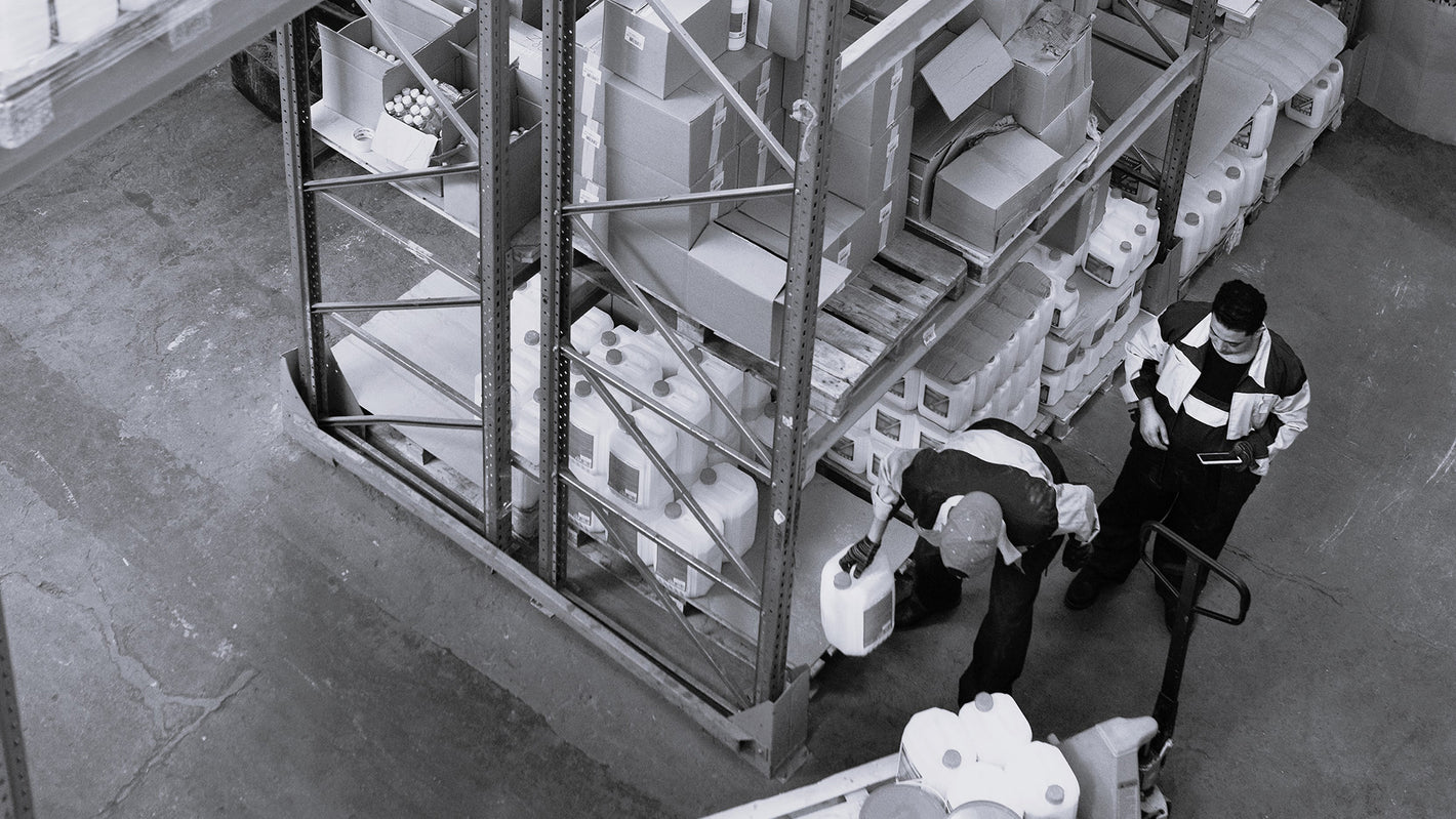 black and white image of warehouse staff taking items off the racking and loading onto a pallet ready for shipping.